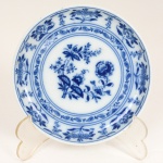PORCELANA PORTUGUESA, um (1) prato decorativo, ornamentação floral na tonalidade azul sobre fundo branco, manufatura VISTA ALEGRE (fundada em 1824, pelo negociante, lavrador, industrial e político, José Ferreira Pinto Basto, através de alvará concedido por D. João VI, tendo seu fundador associado a fábrica os seus 15 filhos, ficando a sociedade denominada Ferreira Pinto & Filhos; cinco anos mais tarde recebe o título real pelo reconhecimento de sua arte e sucesso, ficando conhecida como Real Fábrica da Vista Alegre, começou no fabrico de vidros enquanto se empenhava em esforços para a produção de porcelana, os primeiros ensaios conseguidos foram imperfeitos denominado loiça de pó de pedra, através de boas relações com a fábrica francesa de Sevres conseguiu as receitas para o fabrico de porcelana, somente em 1832, por sorte, é encontrado um jazigo de caulim situado em Aveiro, próximo a Ílhavo, a partir desta data o fabrico de porcelana foi se aperfeiçoando em Portugal, 1851 expôs com sucesso no Palácio de Cristal em Londres; 1852 D. Fernando II visita a fábrica e encomenda uma baixela completa; 1867 recebeu sua primeira premiação na Exposição Universal de Paris; 1880 interrompe a produção de vidros para se dedicar exclusivamente a porcelana; 1964 inauguração do Museu Histórico da Vista Alegre; ainda em funcionamento), medindo 11,5 cm diâmetro.