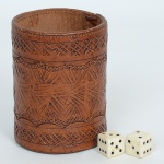 BRINQUEDO, três (3) itens: 1 copo de couro para jogar dados, cilíndrico, ornamentação pirografada, medindo 9 cm altura e 6 cm diâmetro; 2 dados, todos os itens com sinais de uso, vide foto.
