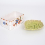 FAIANÇA E PORCELANA, dois (2) itens: 1 caixa retangular sem a tampa, ornamentação floral policromada, arremates a ouro, marca N.K.T. Imperial Ironstone Ware, Made in Japan, medindo 14 x 8 x 5,5 cm, possui o craquelê característico do envelhecimento de toda a faiança; 1 covilhete no formato de folha, marca LE LIS BLANC CASA, medindo 16 x 11,5 cm, tons de verde, todos os itens usados, vide foto.