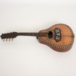 INSTRUMENTO MUSICAL, um (1) antigo bandolim com 8 cordas, adquirido na Ao Cavaquinho de Ouro (Rua da Alfandega 168, RJ), com rica marchetaria com incrustações de madrepérola e madeiras diversas, medindo 58,5 cm, sinais de uso, quebrado, demanda restauro, além de pequenas perdas e defeitos, vide foto.