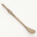 METAL PRATEADO, uma (1) bomba para degustação de chimarrão,  traz marca de dois fabricantes em conjunto: CORNETA (uma das pioneiras em cutelaria no Brasil, fundada pelos irmãos Berg, com tradição no ramo desde 1787 na Alemanha, começou as atividades comerciais no Brasil em 1902 e passou a fabricar aqui a partir de 1932, sofreu intervenção em 1943 devido a Segunda Guerra e a partir de 1948 tornou-se 100% nacional), EBERLE (Abramo Eberle 1880, Monte Magrè 1945, Caxias do Sul, veio com a primeira leva de imigrantes italianos para o Brasil em 1884 junto com seus pais Giuzeppe Eberle e Luigia Zanrosso, seu pai abriu uma pequena funilaria mas como tinha que trabalhar na lavoura quem cuidava era a mãe e o pequeno Abramo ajudava na funilaria; em 1896 quando o pai resolveu vender a funilaria para concentrar os esforços da família na lavoura Abramo, com 16 anos de idade, se propôs a comprá-la do pai, em 1918 já com o nome Abramo Eberle & Cia iniciou a fabricação de talheres e utensílios de mesa, morreu em 1945 com 65 anos de idade e os filhos deram continuidade aos negócios até 1984 quando venderam para o Grupo Zivi), confeccionada em alpacca, patilha fixa, haste cilíndrica, botão de rosa relevado em elementos vegetalistas, boquilha ligeiramente achatada, medindo 22,5 cm comprimento, sinais de uso, vide foto.