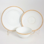 PORCELANA, um (1) trio para chá (xícara, pires e prato de bolo), tonalidade branca, arremates a ouro, manufatura SÃO JOÃO/BRENNAND (fundada por Ricardo Lacerda de Almeida Brennand, na cidade de Recife PE, no ano de 1947, no prédio adaptado da antiga Usina de açúcar São João da Várzea, fechou em 1968), medindo a maior peça 17 cm diâmetro, sinais de uso, vide foto.