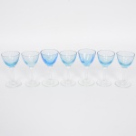 Conjunto de taças de pé alto, para licor, em vidro, bojo de tonalidade azul claro, fuste e base incolores. Composto de sete(07) unidades. Meds.: Alt. 9 x Diam. 4,5 cm.