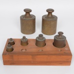 Antigo conjunto de pesos confeccionados em bronze maciço, acomodados em estojo de madeira com encaixes individuais. Composto de duas(02) unidades de 5KG, uma(01) unidade de 1KG, uma(01) unidade de 500G, uma(01) unidade de 200G e duas(02) unidades de 100G.