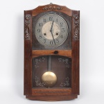 INREBRA. Relógio de parede da década de 1950, fabricação nacional, caixa em madeira bicolor, frontal recortado, talhada com elementos decorativos em reserva, mostrador circular em metal contendo dois furos, numeração arábica, marca da manufatura centralizada(H inserida numa estrela de seis pontas), seção inferior em cristal gravado com flores, que permite a visualização do pêndulo metálico. Movimento mecânico com corda manual, duração de 8 dias, marca as horas cheias com uma batida correspondente e uma batida adicional na meia hora, equipado com sistema de pêndulo oscilante visível. Este modelo pertence à linha nacional de relógios produzida entre as décadas de 1950 e 1970, período em que a INREBRA(Indústria de Relógios do Brasil Ltda) se consolidou como uma das principais fabricantes brasileiras de relógios de parede. Apresenta desgastes e sinais do tempo, visíveis nas fotos. Med.: Alt. 60 x Comp. 35 x Larg. 11,5 cm.