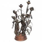 Antiga luminária de mesa, para cinco luzes, composta por grupo escultórico fundido em pétit bronze (liga metálica com acabamento patinado), montada sobre base circular em madeira torneada. A composição central representa casal com vestimentas de época, em trajes do século XVIII, inserido em composição decorativa com elementos curvos de padrão vegetalista. Apresenta desgastes e oxidações visíveis nas fotos. Med.: Alt. 63 x Comp. 46 x Larg. 40 cm. "ESTE LOTE NÃO PODE SER ENVIADO PELO CORREIO"