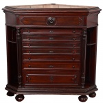 <b>Móvel de canto </b>em madeira nobre, de formato trapezoidal, com tampo chanfrado e base moldurada, apoiada sobre pés tipo bolacha. Frente composta por oito gavetas centrais ladeadas por colunas torneadas e prateleiras laterais embutidas. Bandeja superior com ornamento circular entalhado e ferragens originais em metal patinado. Brasil, final do séc. XIX / início do XX. Med. 123 x 115 x 86 cm