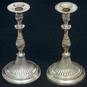 Raro <b>par de castiçais </b>em prata portuguesa neoclássica, apresentando decoração gomada e base circular com filetados. Contraste da cidade do Porto de Alexandre Pinto da Cruz usado de 1810 a 1818 e marca de prateiro não identificada. Um deles necessitando solda e o outro com mínimos amassados do tempo no bocal. Peso 590 gramas. Alt. 23,5 e 24 cm