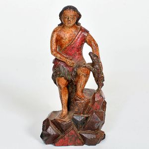 Imagem de <b>São Sebastião </b>em madeira entalhada e policromada, representado sentado sobre afloramento rochoso facetado. O santo veste tanga verde estilizada com panejamento lateral vermelho, deixando o corpo parcialmente desnudo. Com a mão direita segura pequeno animal enquanto apoia a perna esquerda em posição elevada. Alt. 16 cm