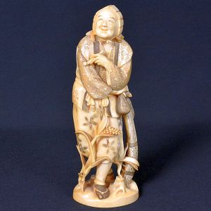 <b>Escultura </b>em marfim representando figura masculina idosa, de expressão alegre e serena, trajando vestes tradicionais ricamente entalhadas com padrões geométricos e florais. Segura cajado com vara de pescar, da qual pende um peixe  símbolo de prosperidade no imaginário oriental. Apresenta selo sob base discreta. Alt. 20 cm
