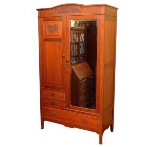 <b>Guarda-roupa </b>em madeira, com frente composta por duas portas  uma lisa com aplique entalhado em motivo floral e outra com espelho bisotado de corpo inteiro. Almofada superior em arco com entalhes decorativos em relevo. Parte inferior com gavetão, laterais lisas e pés ligeiramente arqueados. Med. 201 x 112 x 54 cm