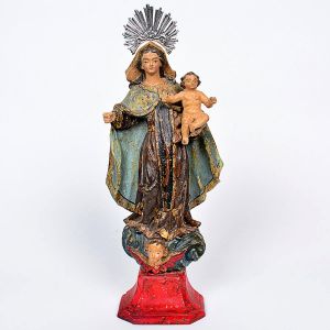 Imagem de <b>Nossa Senhora do Carmo </b>em madeira entalhada em policromia. Veste em plissados espraiada aos pés. O Menino apoia-se sobre a mão esquerda. Sobremanto em azul claro. Realces a ouro. A santa pousa sobre enrolados de nuvens com cabeça de anjo à frente. Base trapezoidal em vermelho. Séc. XVIII. Alt. 33 cm