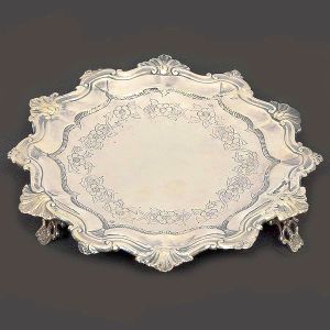 <b>Salva </b>circular em prata portuguesa. Borda recortada decorada com angras intercaladas por elementos concheados. Fundo de centro liso circundado por gravações floridas. Pés vazados. Contraste da cidade de Lisboa de fins do séc. XVIII ou início do XIX e marca ilegível de prateiro. Diâm. 21 cm. Peso 210 gramas