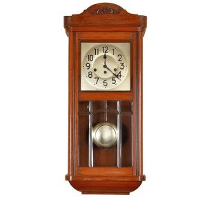 <b>Relógio de parede </b>em madeira, com mostrador metálico prateado de algarismos árabes em relevo e ponteiros recortados. Caixa retangular com frontão superior ornado por entalhe floral e porta frontal envidraçada em duas seções, revelando o pêndulo metálico circular. Acompanha chave de corda. Med. 71 x 30 cm