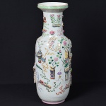 <b>Vaso </b>chinês de corpo cilíndrico com ombros levemente arredondados, em porcelana decorada com esmaltes policromados e elementos em relevo representando símbolos auspiciosos com vasos, pergaminhos, cetros "ruyi", lanternas e frutos. Borda superior com friso geométrico em verde e amarelo. Alt. 62 cm
