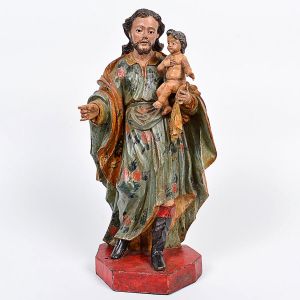 Belíssima imagem de <b>São José de Botas com o Menino</b> em madeira entalhada com rica policromia das vestes decoradas com flores em carmim sobre fundo azul claro. Finas feições e detalhado tratamento dado aos cabelos caído às costas do santo. Olhos em contas e base chanfrada. Séc. XVIII. Alt. 45 cm