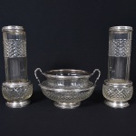 <b>Conjunto de três floreiras </b>em cristal com lapidação geométrica em relevo. Bordas e base guarnecidas em prata francesa ricamente cinzelada com frisos e ornamentos fitomórficos. Composto por duas floreiras de formato cilíndrico e "bowl" com alças. Alt. da floreira 37 cm cm;  Alt. do "bowl" 23 cm