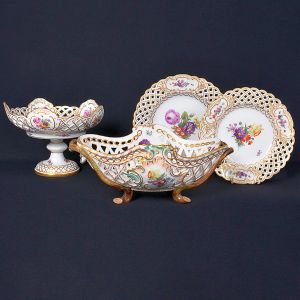 <b>Serviço de jantar</b>  em porcelana dinamarquesa. Bordas vazadas decoradas com frisos dourados e flores em reservas. Constando de 18 pratos rasos, 11 pratos de sobremesa, 1 fruteira de pé alto e 2 fruteiras de formato navicular. Nos versos marca da manufatura de Royal Kopenhagen.Total de 32 peças.