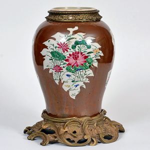 <B>Vaso </b>de formato balaústre em porcelana chinesa da Companhia das Índias do tipo "Batavian Ware", decorado com reservas florais em policromia de esmaltes da Família Rosa sobre fundo monocromático "café au lait". Reinado Qianlong (1736-1795). Colar e base em bronze lavrado. Alt. do vaso 30 cm
