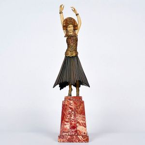 <b>Demetre Chiparus</b><Br>(18861947)<Br>Escultura Art Déco criselefantina, em marfim e bronze patinado. Representando bailarina em movimento, com braços erguidos. Traja vestido plissado e adereços orientais, ricamente detalhados. Base em mármore vermelho veteado. França, circa 1925. Alt. 38 cm