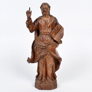 Bela imagem de <b>Santo Apóstolo </b>executada em madeira com vestes ricamente entalhadas. A mão direita com o polegar e o indicador juntos, representam a união das naturezas divina e humana em Cristo. Na mão esquerda um evangelho. Olhos em contas. Séc. XVIII. Alt. 37 cm