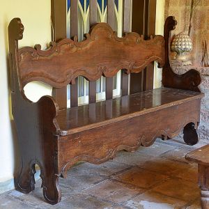 <b>Banco </b>em madeira entalhada, ao gosto colonial luso-brasileiro, com encosto alto recortado em volutas e laterais fechhadas em apoios de braço integrados à estrutura. Assento reto apoiado sobre base com saia sinuosa e pés recortados. Med. 109 x 177 x 42 cm