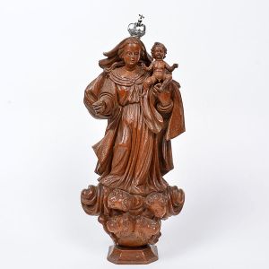 Imagem de <B>Nossa Senhora do Rosário </B>em madeira entalhada com elaboradas vestes plissadas e espraiadas aos pés. A imagem pousa em cabeças de nuvens com quatro cabeças de anjinhos. Olhos em contas e base chanfrada. Coroa em prata. Séc. XVIII. Alt. 35 cm