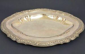 Belíssima <b>bacia de "água às mãos" </b>em prata portuguesa. Fundo liso e aba movimentada decorada com volutas e concheados envolvendo friso interno perolado. Contraste da cidade de Lisboa da segunda metade do séc. XVIII. Peso 2.000 gramas. Med. 55 x 41 cm