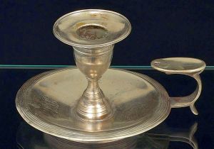 <B>Palmatória </B>em prata portuguesa, apresentando decoração lisa com bordas filetadas e monogramada. Contraste da cidade de Lisboa do início do séc. XIX e marca ilegível de prateiro. Falta o abafador. Pequena mossa na borda. Alt. 8 cm. Peso 250 gramas.