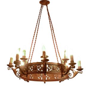 <b>Lustre </b>em ferro forjado, de corpo circular vazado com reservas ovais e volutas em relevo. Braços sinuosos, cada um com "bobéche" em concha e porta-lâmpada em formato de vela. Suspenso por correntes duplas. Apresenta pátina original com desgastes. Alt. 120 cm