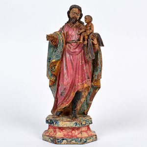 Imagem de <b>São José de Botas com Menino</b>, em madeira entalhada, apresentando vestes em exuberante e variada policromia florida, entrevendo-se os altos coturnos. Belo tratamento dos cabelos caídos às costas. Base marmorizada. Séc. XIX. Alt. 25 cm