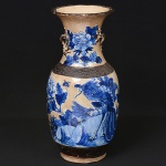 <b>Vaso</b> em faiança esmaltada decorada com representação de aves entre ramagens floridas, em tonalidades de azul cobalto. Alças laterais em relevo com formato de galhos. Bordas com frisos em bronze. Apresenta ideograma chinês na base. Alt. 47 cm