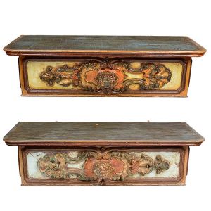 <b>Par de belos consoles sacros</b>, de parede, de forma retangular em madeira patinada e entalhada com elementos barrocos inseridos em almofadados. Policromia de época em tons de azul, verde e vermelho. Séc. XVIII. Med. 33 x 117 x 49 cm