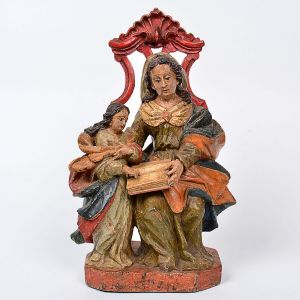 Linda imagem de <B>Sant'Ana Mestra </B>em madeira patinada predominando tonalidades de azul e vermelho. Panejamento das vestes movimentadas em entalhes oblíquos. Exuberante cadeiral vazado, encimado por volutas. Séc. XVIII. Alt. 29,5 cm