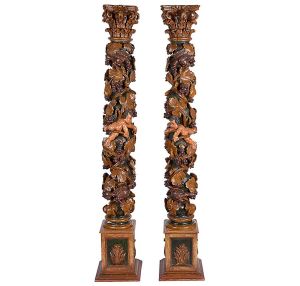 <b>Par de colunas </b>em madeira esculpida e policromada, ornamentadas por uvas, ramos de videira e anjinhos em alto relevo, e rematadas por capitéis dóricos. Bases retangulares almofadadas com bordas em degraus. Séc. XIX. Alt. 177,5 cm