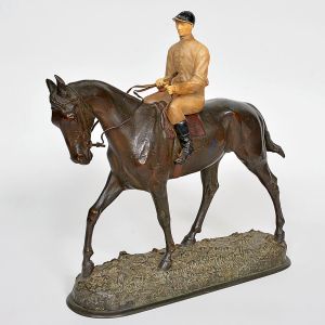 <b>M. FIOT - Escultura </b>representando cavaleiro montado em cavalo ao passo, com figura do jóquei em policromia clara, contrastando com o cavalo em bronze patinado escuro, sobre base modelada em relevo. Assinada na base. Alt. 35 cm