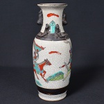 <b>Vaso </b>em porcelana chinesa craquelê, decorado com guerreiros a cavalo. Corpo cilíndrico com bojo levemente afunilado e gola aberta, apresentando esmalte em tom marfim. Base com marca incisa em caracteres orientais. Alt. 25 cm