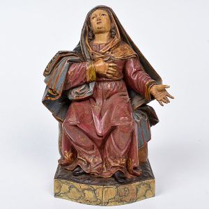 Imagem de <b>Nossa Senhora das Dores </b>ricamente entalhada com manto e sobremanto plissados e belamente espraiados aos pés. Realces do entorno com volutas a ouro. Feições voltadas ao céu. Base marmorizada. Séc. XVIII. Alt. 21 cm