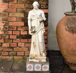 <b>Escultura </b>em cerâmica da Fábrica de Santo Antônio do Porto, representando "Erato", figura feminina clássica. Assentada sobre base revestida com azulejos decorativos. Peça com desgaste natural do tempo e diversos lascados.