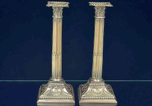 <B>Par de castiçais </B>em prata modelados em colunas coríntias. Apresentam haste filetada e base com guirlandas e perolados. Marcas parciais da cidade do Porto da segunda metade do séc. XIII. Peso 630 gramas. Alt. 25,5 cm