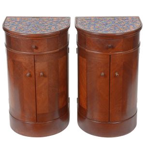 <b>Par de mesinhas de cabeceira </b>em mogno, com formato semicircular e tampo revestido em tecido estampado floral. Apresenta uma gaveta superior e porta dupla inferior, ambas com puxadores torneados. Med. 74 x 43 x 36 cm