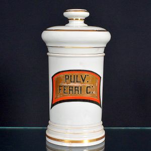 <b>Pote de farmácia </b>em porcelana branca, com corpo cilíndrico e detalhes em filetes dourados. Cartela frontal pintada nas cores vermelho, dourado e preto com inscrição "PULV: FERRI C:". Apresenta restauro na tampa.