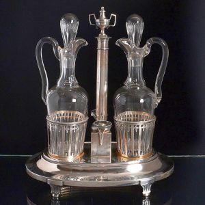 <b>Galheteiro </b>com montagem em prata francesa decorada ao gosto neoclássico tendo o topo modelado em forma de ânfora. Recipientes em cristal. Contrastes da cidade de Paris e marca do prateiro D. S. R. Alt. 30,5 cm