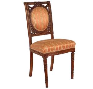 <b>Cadeira </b>em madeira entalhada, com espaldar emoldurado por motivos florais, encimado por grinalda de laços e flores. Assento estofado em tecido listrado em tons de dourado e pêssego. Estilo Luís XVI. Alt. 93 cm