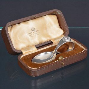<b>Colher infantil </b>em prata inglesa, acondicionada em estojo original. Peça de desenho clássico, com cabo curvado terminado em emblema ornamental. Apresenta marcas da cidade de Sheffield e da casa Mappin & Webb.