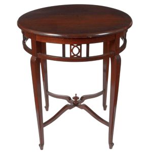 <b>Mesa redonda </b>em madeira, de linhas delicadas, apresentando saia vazada com elementos geométricos recortados e pés finos levemente arqueados, unidos por cruzeta central com pináculo torneado. Med. 76 x 65 cm