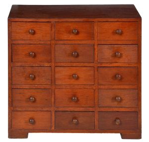 <b>Móvel contador </b>em madeira, com estrutura retangular lisa apoiada sobre sapatas blocadas. Frente composta por quinze gavetas de igual tamanho, todas com puxadores em forma de botão. Med. 51 x 55 x 30 cm