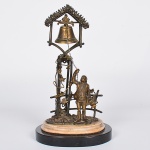 <b>Escultura </b>decorativa em bronze representando jovem camponês acionando sino suspenso. Estrutura com treliças e folhagens, sobre base circular em mármore e madeira. Séc. XIX / início do XX. Alt. 26 cm