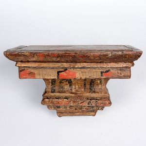 <b>Peanha </b>em madeira, com vestígios de policromia antiga em tons de ocre, vermelho e verde, apresentando recortes em degraus e reforço metálico posterior para fixação em parede. Med. 15 x 25 cm