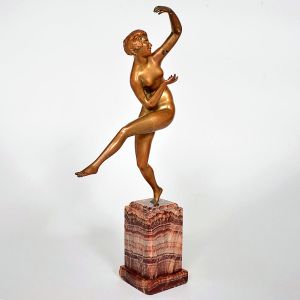 <b>Escultura em bronze </b>patinado representando figura feminina em pose de dança, de traços estilizados ao gosto Art Déco. Apoiada sobre base em ônix rajado. Artista não identificado. Alt. 35 cm
